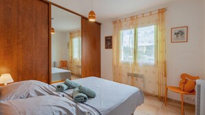 A bedroom with a bed, a chair, a heater, and a window with curtains.