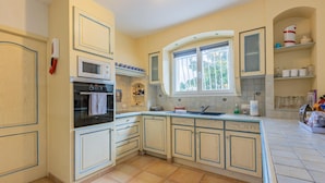 A kitchen with a built-in oven, microwave, and a window with curtains.