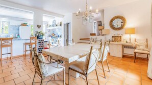 Une cuisine spacieuse avec un coin repas, comprenant une grande table, des chaises et un lustre.