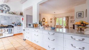 Une cuisine spacieuse avec des meubles blancs, un grand îlot central et une horloge au mur.