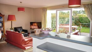 A living room with a red sofa, a television, a coffee table, and a large window with curtains. - Résidence les Dunes du Golf (Wimereux)