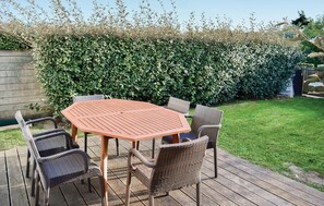 Une terrasse extérieure en bois avec une table ronde et des chaises en osier.