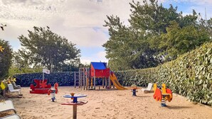 A sandy playground with a slide, climbing structures, and swings. - Résidence les Dunes du Golf (Wimereux)