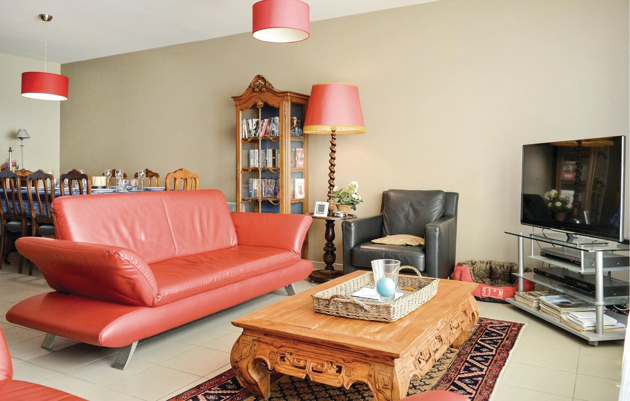 Un salon avec un canapé rouge, une table basse en bois, un téléviseur et une bibliothèque.