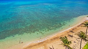 Ein Strand mit klarem türkisblauem Wasser, einem Sandstrand und Palmen.