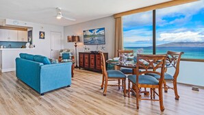 Ein Wohnzimmer mit Sofa, Esstisch, Stühlen und Blick auf den Ozean.