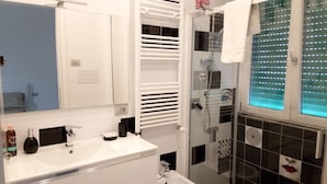 Une salle de bain moderne avec un meuble-lavabo blanc, une douche en verre et des carreaux décoratifs.