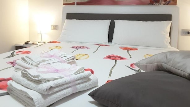 Un lit bien fait, recouvert d’une courtepointe à motifs floraux, avec une pile d’essuie-tout et un oreiller posé sur le côté.