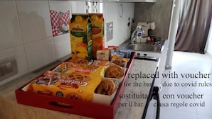 Une cuisine avec un plateau de collations comprenant des barres chocolatées et des gaufres, ainsi qu’un avis concernant le remplacement des bons en raison des règles liées à la COVID.
