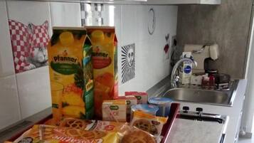 Una cocina con una bandeja de aperitivos que incluye barras de chocolate y gofres, y una nota sobre el reemplazo de vales debido a las normas de COVID.