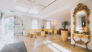 Un hall espacioso con un espejo grande, zona de estar y mostrador de recepción.
