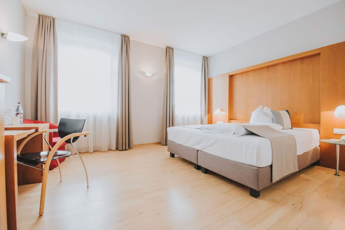 A hotel room with a bed, a desk, and a chair.