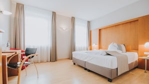 Una habitación de hotel con una cama, un escritorio y una silla.