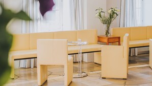 Un hall de hotel con un sofá amarillo, una mesita y un jarrón con plantas.