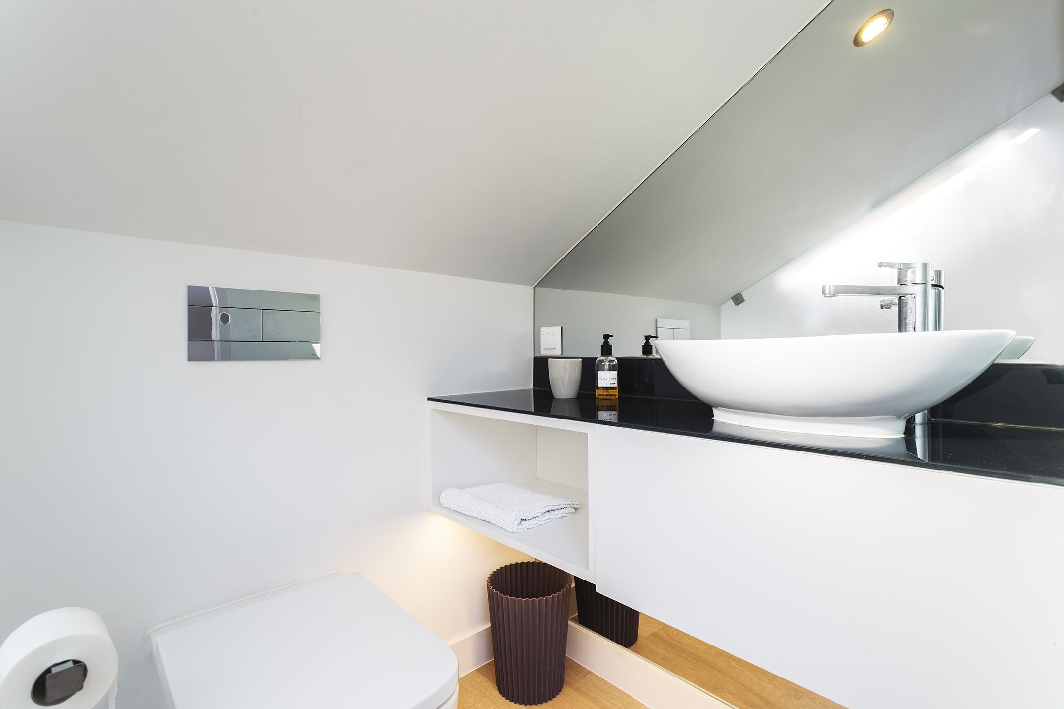 A modern bathroom with a white sink, black countertop, and a mirror above.