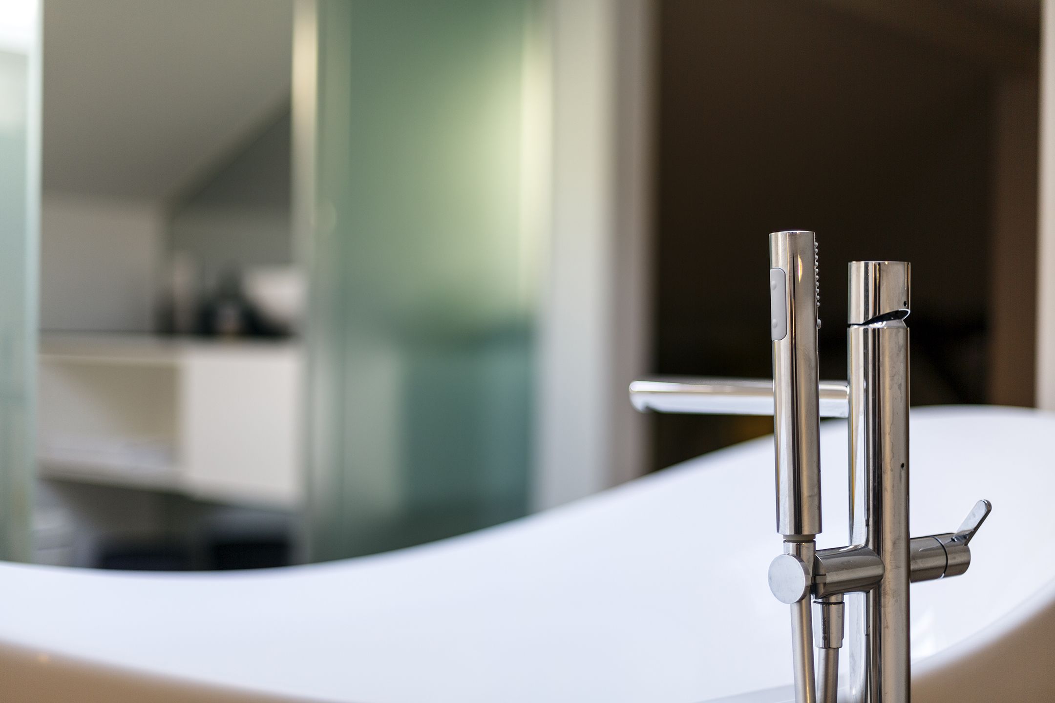 A modern bathroom with a white bathtub, chrome fixtures, and a glass shower enclosure.