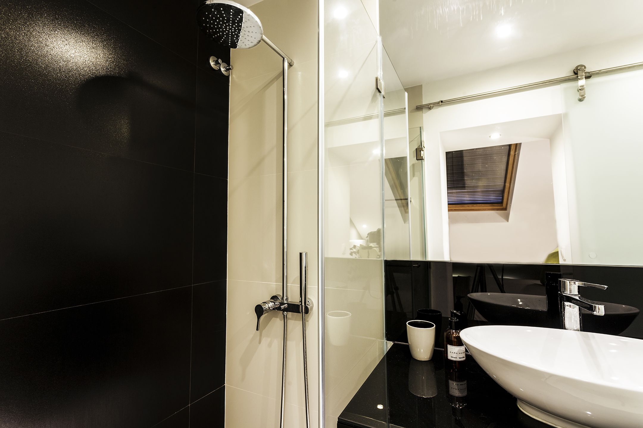 Une salle de bain moderne avec une douche à parois de verre, un plan de toilette noir et un lavabo blanc.