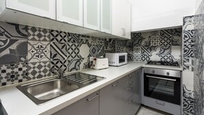 A kitchen with a stainless steel sink, white cabinets, a microwave, and an oven. - Fanqueiros Deluxe Apartment (Lisbon)