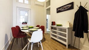 A dining area with a white table, red and white chairs, a white shelving unit, and a black coat rack. - Fanqueiros Deluxe Apartment (Lisbon)