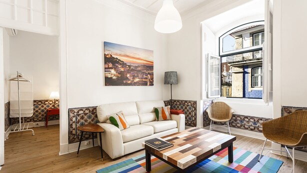 A modern living room with a white sofa, a wooden coffee table, and a colorful striped rug. - Fanqueiros Deluxe Apartment (Lisbon)