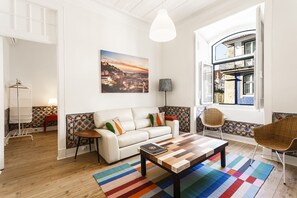 Een moderne woonkamer met een witte bank, een houten salontafel en een kleurrijk gestreept vloerkleed.
