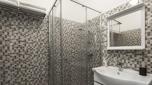 A bathroom with a glass-enclosed shower, a white sink, and a tiled backsplash. - Fanqueiros Deluxe Apartment (Lisbon)