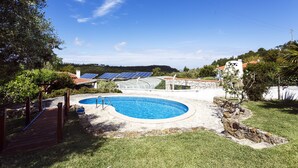 Patio con piscina, paneles solares y terraza de madera.
