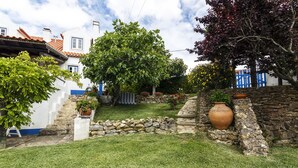 Un patio con un muro de piedra, un árbol grande y una planta en maceta.
