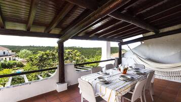 Enjoy a peaceful dining experience on this serene outdoor terrace, surrounded by lush greenery and a scenic view.