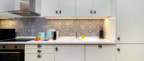 A modern kitchen with white cabinets, a patterned backsplash, and stainless steel appliances.