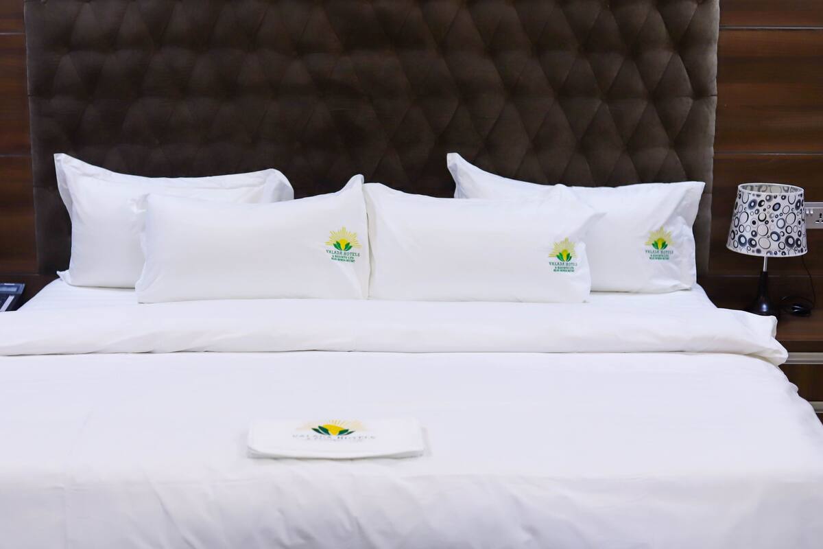 A neatly made bed with white bedding and pillows, each featuring a logo.