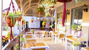 Un restaurante con terraza, plantas en macetas y un piso de madera.