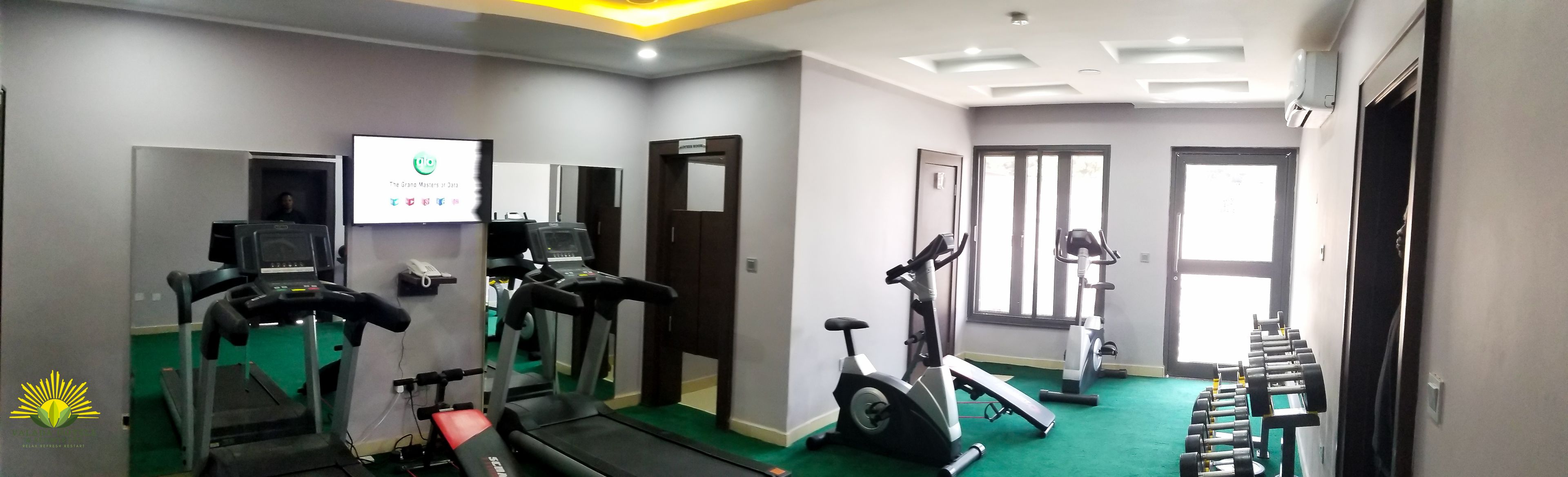 A gym with treadmills, an elliptical, and dumbbells.