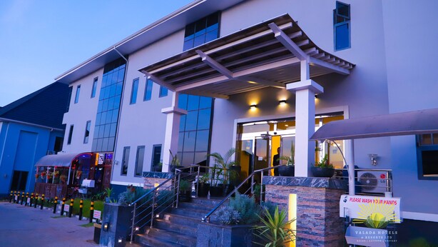 Una entrada de hotel moderna con una escalera cubierta, zona de estar al aire libre y un letrero para Valada Hotels & Resorts Ltd.