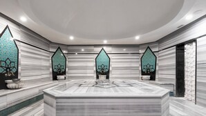 Un bagno moderno con un mobile vanitario in marmo, piastrelle geometriche e illuminazione a incasso.