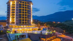 Um hotel alto com várias varandas e área de piscina no terraço.