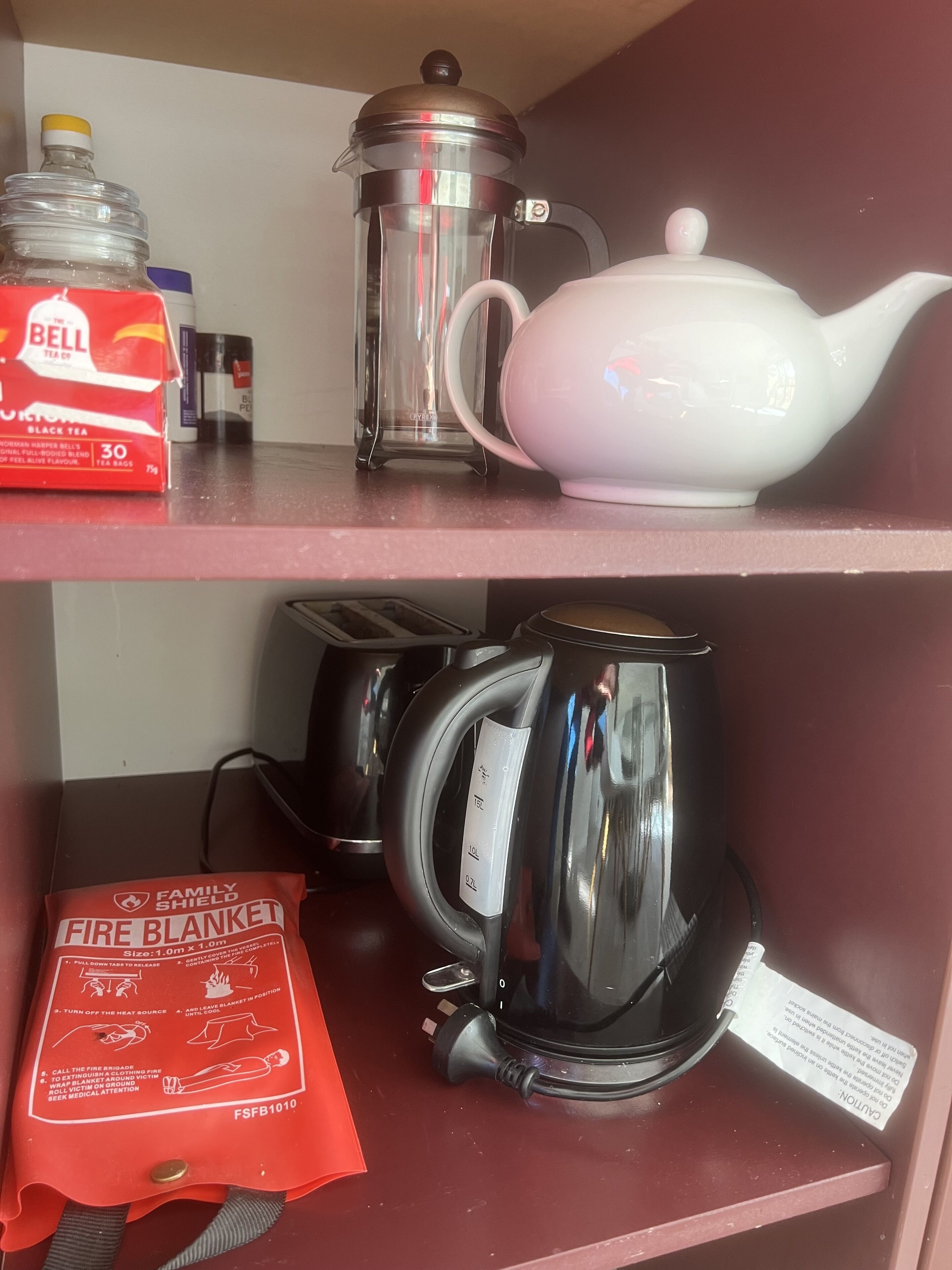 Ein Küchenregal mit Kaffeemaschine, Teekanne, Wasserkocher und Brandschutzdecke.