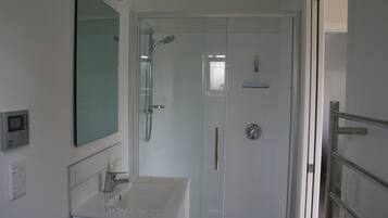 Een moderne badkamer met een douchecabine van glas, een witte wastafel en een grote spiegel.