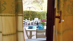 An outdoor dining area with a table set for two, white chairs, and a white umbrella. - Santa Margherita di Pula: terraced house with garden 200 meters from the sea (Pula)