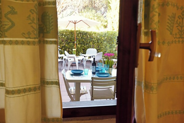 An outdoor dining area with a table set for two, white chairs, and a white umbrella. - Santa Margherita di Pula: terraced house with garden 200 meters from the sea (Pula)