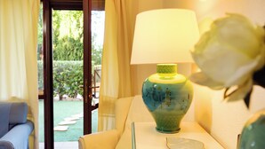A room with a sofa, a table with a lamp, and a view of a garden through a glass door. - Santa Margherita di Pula: terraced house with garden 200 meters from the sea (Pula)