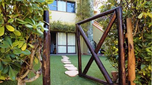 A wooden gate leading to a courtyard with a stone pathway and greenery. - Santa Margherita di Pula: terraced house with garden 200 meters from the sea (Pula)