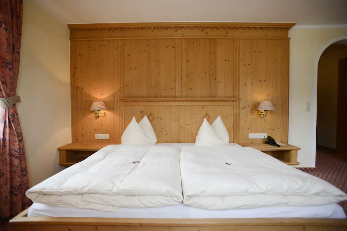 A double bed with a wooden headboard, two bedside tables with lamps, and a floral curtain.