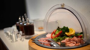 A meal setup with a clear dome cover, a plate of sliced meats, vegetables, and a lemon slice. - Alpengasthof zur Post GmbH (Schattwald)