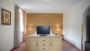 A room with a wooden cabinet, a television, and two wall-mounted lamps. - Alpengasthof zur Post GmbH (Schattwald)