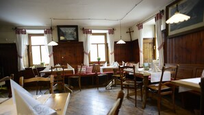 A dining area with wooden tables and chairs, white tablecloths, and hanging pendant lights. - Alpengasthof zur Post GmbH (Schattwald)