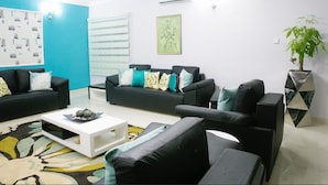A modern living room with black sofas, a white coffee table, and a patterned rug. - Droptop Suites (Lekki)