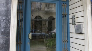 A blue door with a glass panel, a metal gate, and a small mailbox on the wall. - Charming Acropolis Metro Apartment (Athens)