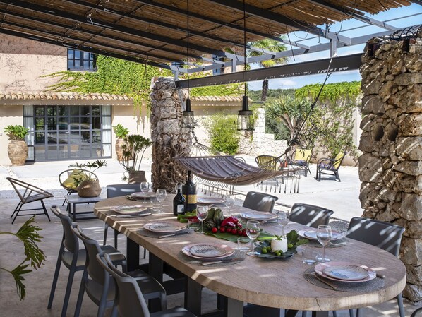 An outdoor dining area with a stone table, chairs, and a hammock.