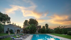 A pool area with lounge chairs, a swimming pool, and a building with a stone facade. - Calm and serenity in the heart of a nature reserve, 5 km from the sea. (Noto)